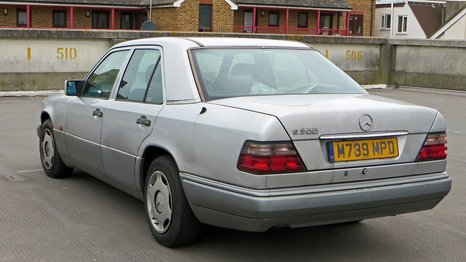 Mercedes-Benz W124 E200 saloon parked on a UK street — the archetypal daily driver classic car